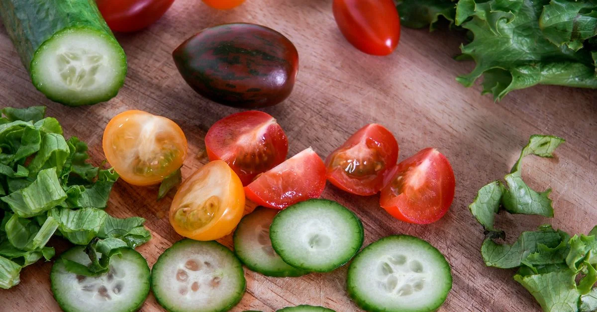 Un assortiment vibrant de légumes frais tranchés sur une planche à découper en bois, parfait pour des salades saines.