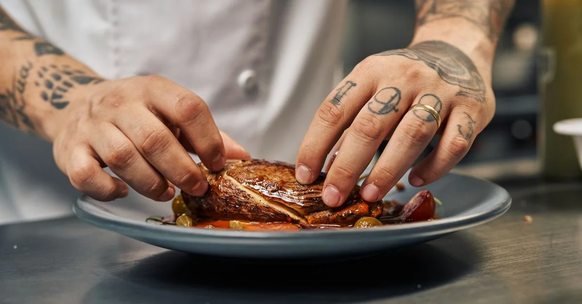 Chef disposant habilement un plat gourmet sur une assiette, mettant en valeur la créativité culinaire.